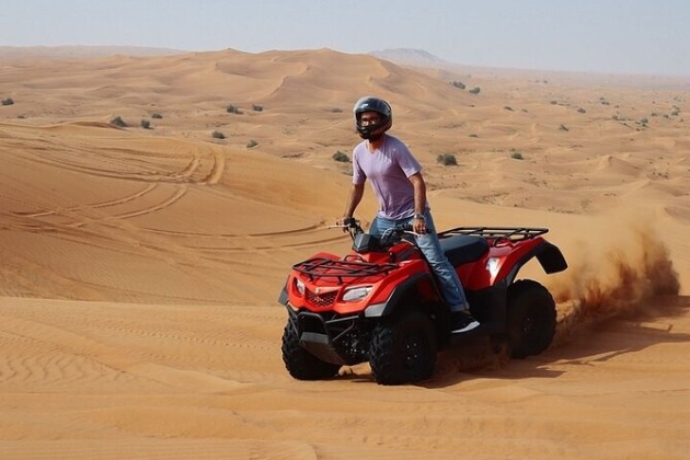 Tourists enjoying a desert safari ride across sand dunes at sunset.