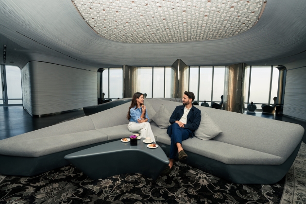 couple relaxes in the luxurious lounge on Level 148 of the Burj Khalifa, enjoying VIP SKY Experience amenities in an elegant, modern setting with panoramic views.
