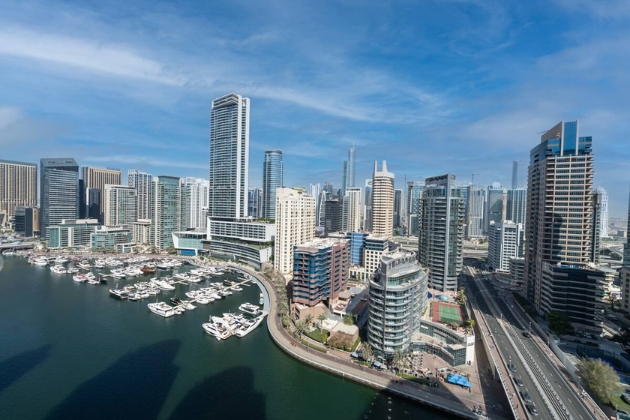 Scenic view of Dubai Marina waterfront with luxury yachts, sparkling waters, and modern skyscrapers along the Marina Promenade.