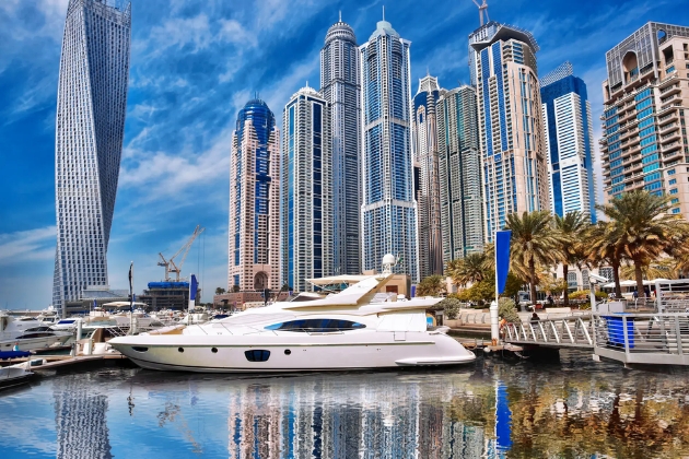 Luxury white yacht docked in Dubai Marina with modern skyscrapers reflecting on the water.