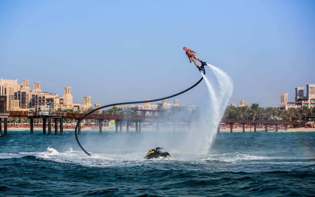 Person performing flyboarding tricks above the water with powerful water jets in Dubai.